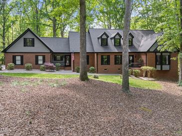 Charming brick home featuring black shutters, complemented by lush landscaping and mature trees in a serene setting at 12537 Birchfalls Dr, Raleigh, NC 27614