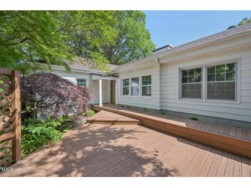 This charming home boasts a spacious wooden deck and inviting backyard with lush greenery and mature trees at 1316 Glenwood Ave, Raleigh, NC 27605