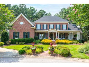 Stately brick home features a covered porch, lush landscaping, and manicured lawn at 1501 Samuel Wait Ln, Wake Forest, NC 27587