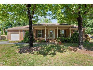 Charming brick home with a covered porch, mature trees, and well-maintained landscaping at 1612 Regency Dr, Burlington, NC 27215