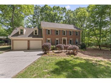 Two-story brick home featuring a two-car garage, dormer windows, and landscaped front yard at 1705 Bridgeport Dr, Raleigh, NC 27615
