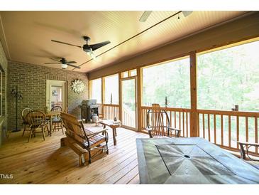 Covered outdoor patio with ceiling fans, brick accents, and wood furniture for relaxing and entertaining at 197 W Paige Wynd Dr, Angier, NC 27501