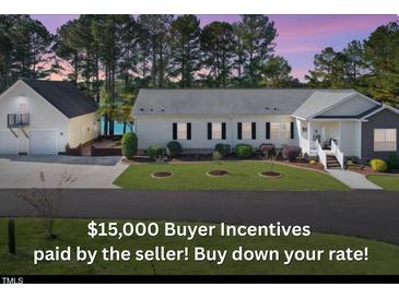 Charming single-story home with a well-manicured lawn and a separate garage, situated near a serene lake at 215 Collins Rd, Lillington, NC 27546