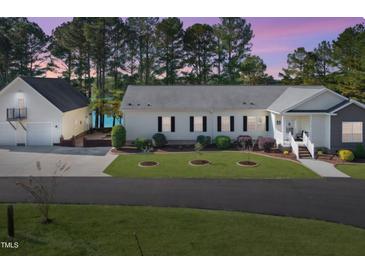 Charming home featuring an attached garage and a well-manicured front yard with a lake view, perfect for peaceful living at 215 Collins Rd, Lillington, NC 27546