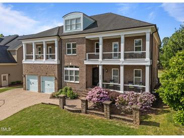 Stunning two-story brick home featuring double balconies, lush landscaping, and a two-car garage at 2820 Charleston Oaks Dr, Raleigh, NC 27614
