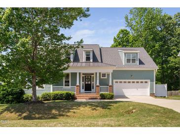 Charming two-story home boasts a quaint front porch, lush lawn, and attached garage at 304 Nelson Ln, Clayton, NC 27527