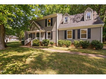 Charming two-story home with grey siding, black shutters, a well-manicured lawn and mature trees at 3113 Chelmshire Ct, Raleigh, NC 27610