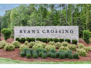 Stone entrance sign for Ryan's Crossing with beautiful landscaping and a natural, wooded backdrop at 480 Lila Dr, Pittsboro, NC 27312