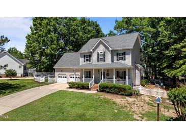 Charming two-story home with a welcoming front porch, landscaped yard, and white picket fence at 6509 Virgilia Ct, Raleigh, NC 27616