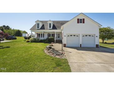 Charming two-story home with a manicured lawn, white siding, double garage, and welcoming front porch at 79 Blande Dr, Kenly, NC 27542