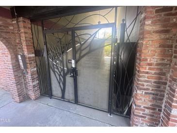 Brick entrance gate with artistic metalwork and concrete stairs, blending security with design at 807 W Trinity Ave # 144, Durham, NC 27701