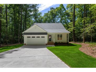 Charming, single-story home with an attached garage, nestled in a wooded lot with a well-manicured lawn and concrete driveway at Lot 3260 Yorkshire Cir, Sanford, NC 27332