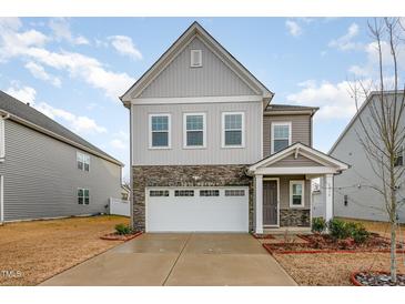 Two-story home featuring stone accents and a two-car garage on a sunny day at 1016 Matterhorn Dr, Fuquay Varina, NC 27526