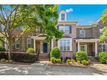 Charming brick townhouse with manicured landscaping, covered entrance, and a beautifully blue summer sky at 1103 Weston Green Loop, Cary, NC 27513
