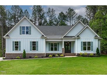 Charming single-story home featuring light blue siding, a gray roof, and lush green lawn at 1218 Red Cedar Ct, Youngsville, NC 27596