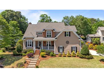 Charming two-story home with a welcoming front porch and beautifully landscaped front yard with mature trees at 1437 Chelton Oaks Pl, Raleigh, NC 27614