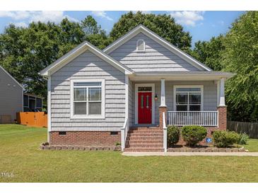 Charming home featuring a brick foundation, red front door, and a cozy front porch with white railing at 209 Mccarthy Dr, Clayton, NC 27527
