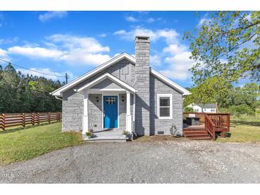 Charming home featuring a stone facade, blue front door, stone chimney, and a well-maintained gravel driveway at 2501 Ferrell Rd, Durham, NC 27704