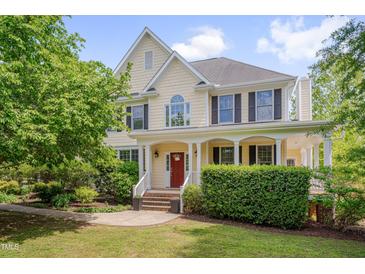 Stately two-story home featuring a manicured lawn, charming front porch, and a red front door at 303 Crooked Meadow Ln, Hillsborough, NC 27278
