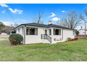 Charming single-story home featuring a brick exterior, black trim, and a well-maintained front lawn under a blue sky at 311 Nc 56, Louisburg, NC 27549