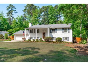 Charming white brick home with grey shutters, manicured lawn, and an American flag displayed at 4109 Huckleberry Dr, Raleigh, NC 27612