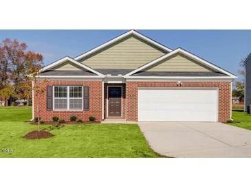 Charming brick home features a well-manicured lawn and an attached garage at 493 Lochalsh Dr, Gibsonville, NC 27249