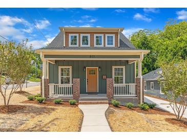 Charming green home featuring a welcoming front porch and well-manicured landscaping at 801 N Elm St, Durham, NC 27701