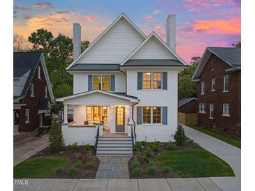 Inviting two-story home featuring a manicured lawn and a charming facade with blue shutters and stone walkway at 909 N Gregson St, Durham, NC 27701