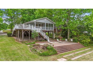 Charming lake house featuring a screened porch, spacious deck, and a brick patio at 104 Pontiac Cv, Louisburg, NC 27549