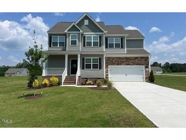 Traditional two-story home with stone accents, attached garage, and a well-manicured lawn at 11412 International Dr, Middlesex, NC 27557