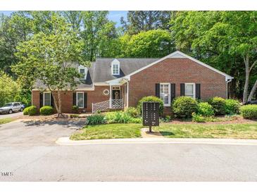 Charming one-story brick home with dormer windows, black shutters, and a nicely landscaped front yard at 1623 Village Glenn Dr, Raleigh, NC 27612