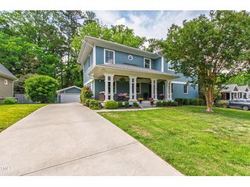 Charming blue two-story home featuring a welcoming front porch, manicured lawn, and ample driveway space at 2517 Medway Dr, Raleigh, NC 27608