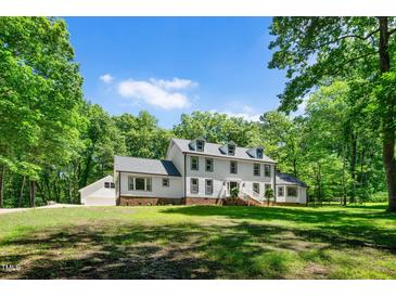 Charming two-story home with landscaped yard surrounded by lush greenery and a long driveway at 318 Hepowil Trce, Hillsborough, NC 27278