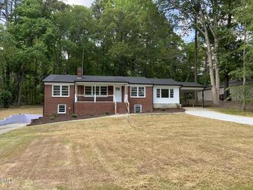 Charming brick home featuring a covered porch, carport, and a spacious front yard surrounded by mature trees at 502 Burton St, Fuquay Varina, NC 27526