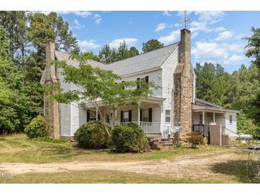 Two-story home with a rustic stone chimney and a covered front porch offering curb appeal at 5062 Dorsey Rd, Oxford, NC 27565