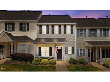 Charming townhome featuring gray siding, black shutters, a cozy front porch, and an American flag at 831 S White St, Wake Forest, NC 27587