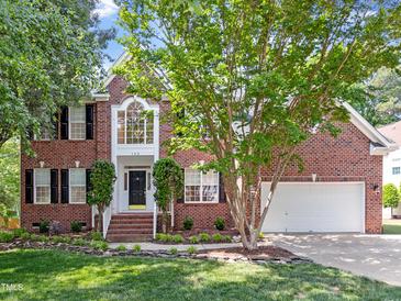 Charming two-story brick home featuring a manicured lawn, symmetrical design, and attached two car garage at 102 Downing Forest Pl, Cary, NC 27519