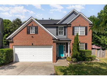 Charming brick home with a two-car garage, teal door, and well-manicured landscaping at 1101 Washhouse Ln, Wake Forest, NC 27587
