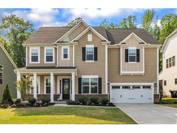 Charming two-story home with a well-manicured lawn, covered porch and attached two car garage at 112 Serenata Dr, Holly Springs, NC 27540