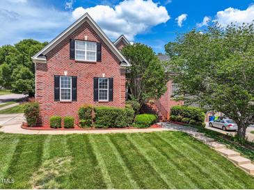 Charming two-story red brick home featuring a well-manicured lawn and lush landscaping with mature trees at 11916 Deneb Ct, Raleigh, NC 27614