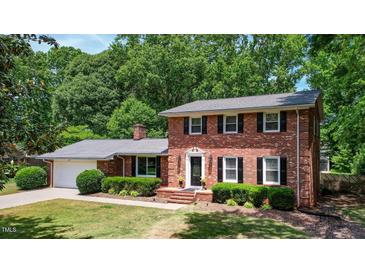 Charming red brick home featuring a well-manicured lawn, mature trees, and classic black shutters at 1274 Candlewood Dr, Elon, NC 27244