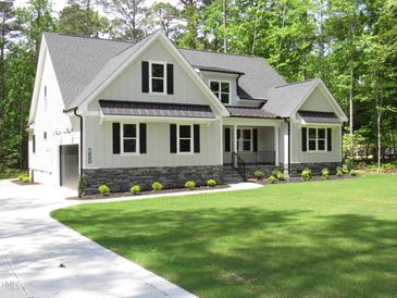 Charming home features a well-manicured lawn, neutral paint, black shutters, and stone accents at 1430 Clifton Pond Rd, Louisburg, NC 27549