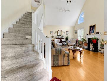 Bright living room with hardwood floors, fireplace, vaulted ceiling, and staircase at 17 Nicklaus Way, Clayton, NC 27520