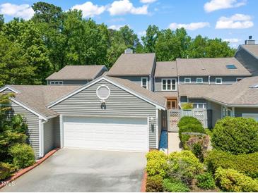 Charming home featuring a pristine white garage door, complemented by lush landscaping and mature trees at 2303 Upper Oaks Way, Raleigh, NC 27615
