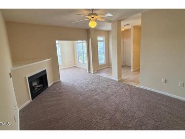 Spacious living room featuring neutral tones, a ceiling fan and a cozy fireplace at 2521 Friedland Pl # 301, Raleigh, NC 27617
