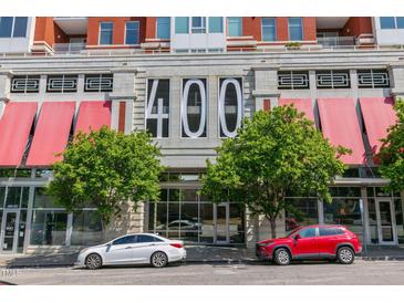 Street view of a modern building with large windows and red awnings providing shade on a sunny day at 400 W North St # 1134, Raleigh, NC 27603