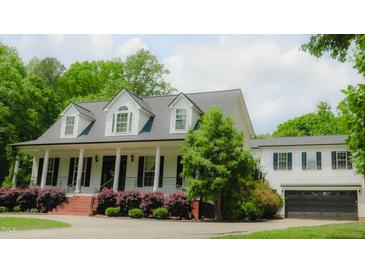 Charming two-story home boasts a classic white exterior, attached two-car garage and a welcoming covered front porch at 42 Miry Branch Ct, Garner, NC 27529