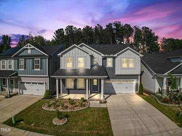 Charming two-story home with a manicured lawn and a two car garage under a dusk sky at 425 Shadow Falls Dr, Wendell, NC 27591