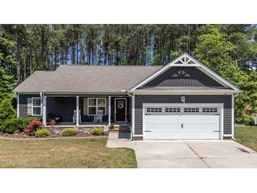 Charming home featuring a covered front porch with landscaping and an attached two-car garage at 60 Northdale Ct, Louisburg, NC 27549