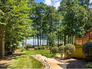 Landscaped backyard featuring a lake view, lush lawn, and a charming wooden walkway at 901 Edgewater Dr, Garner, NC 27529